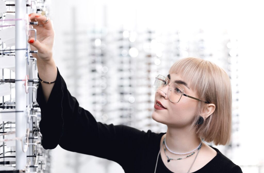 A trendy person browses glasses at their optometrist.