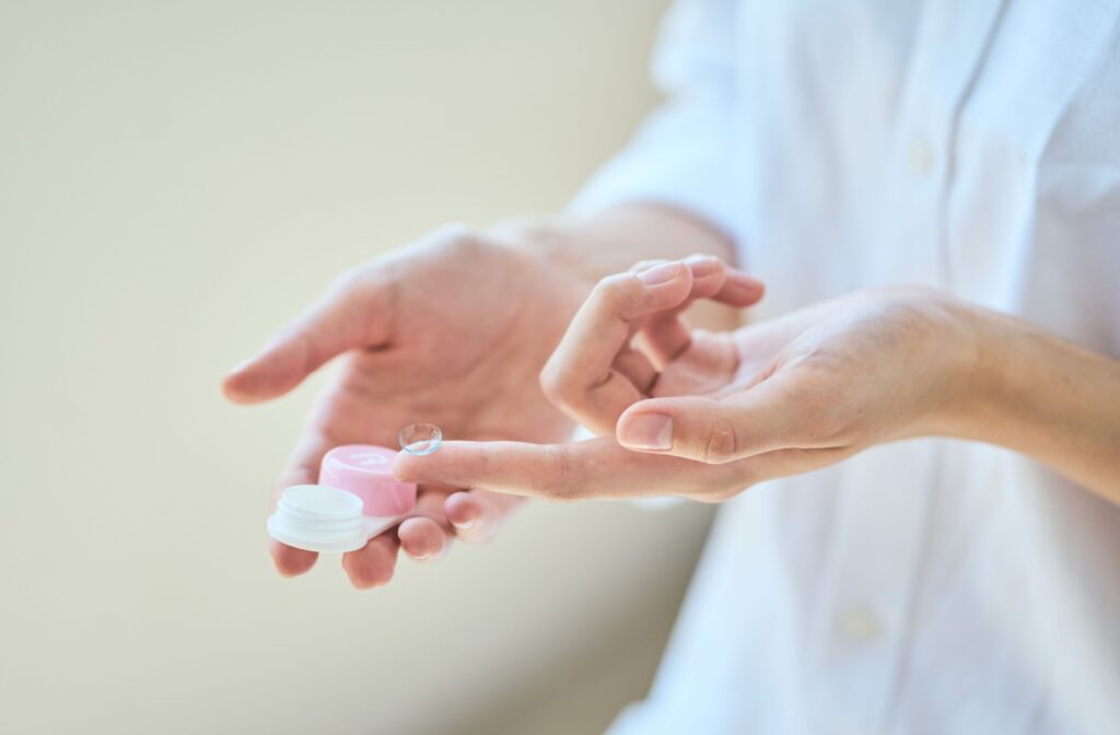 Close up of someone's hands holding a contact lens and a contact lens case.