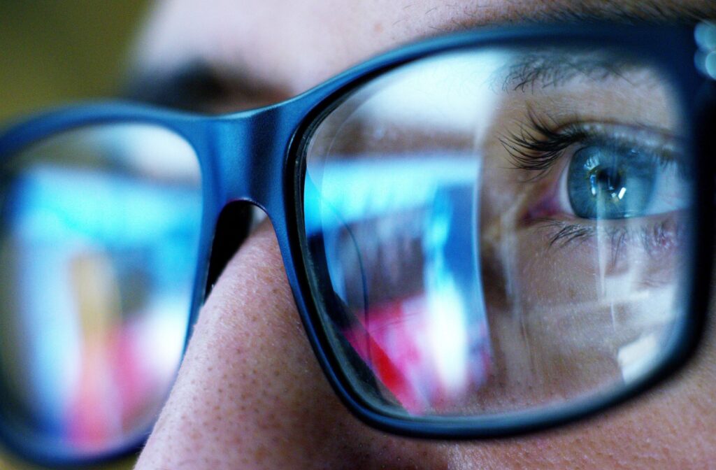 Close up of glasses reflecting a tv screen in the lenses