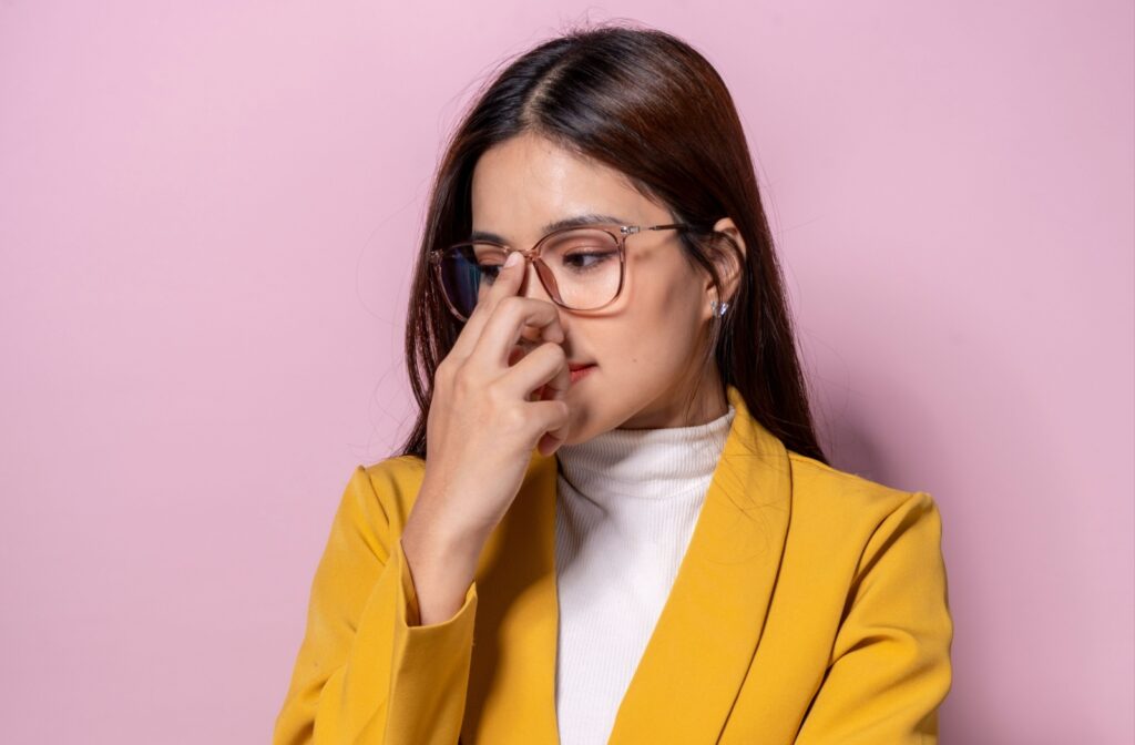 Woman in yellow blazer pushes her glasses up using her index finger