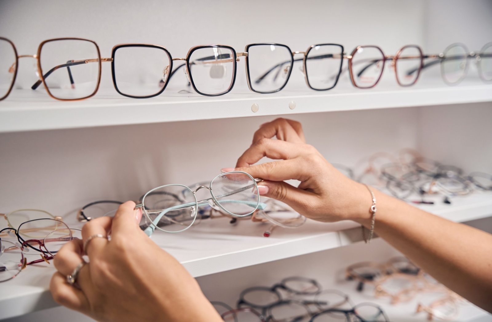 Person picking out a pair of thin metal framed glasses